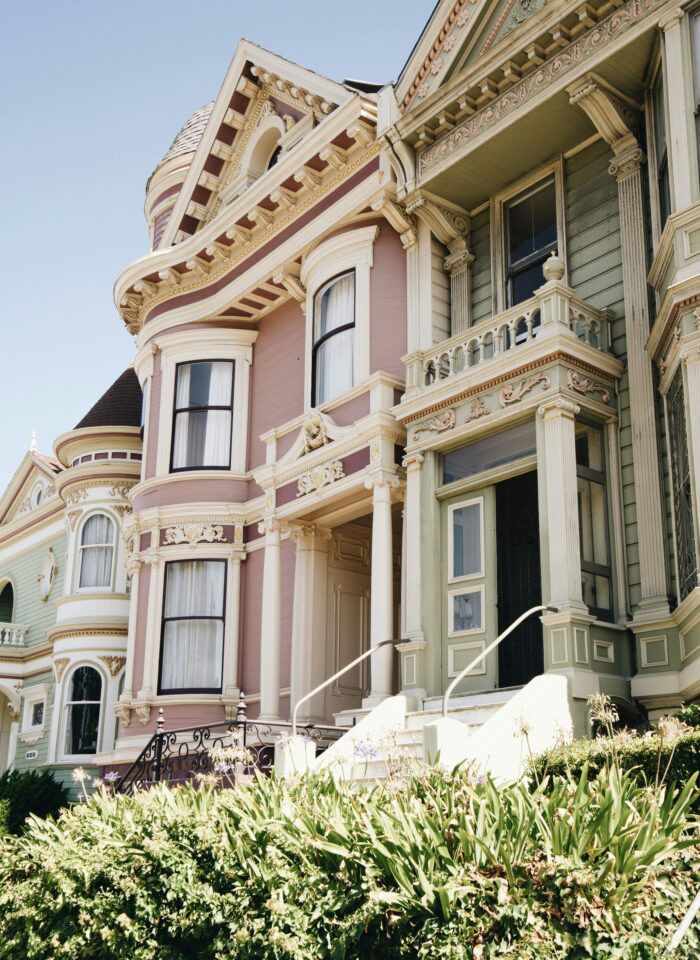 Exterior of a pastel Victorian-style house with ornate trim, bay windows, and original architectural details showcasing the charm of historic homes.