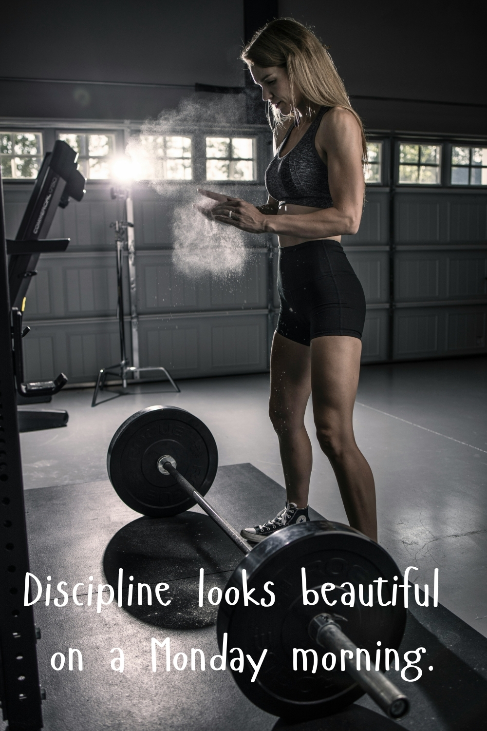 Woman preparing to lift weights in a gym with chalk dust in the air and the quote “Discipline looks beautiful on a Monday morning.”