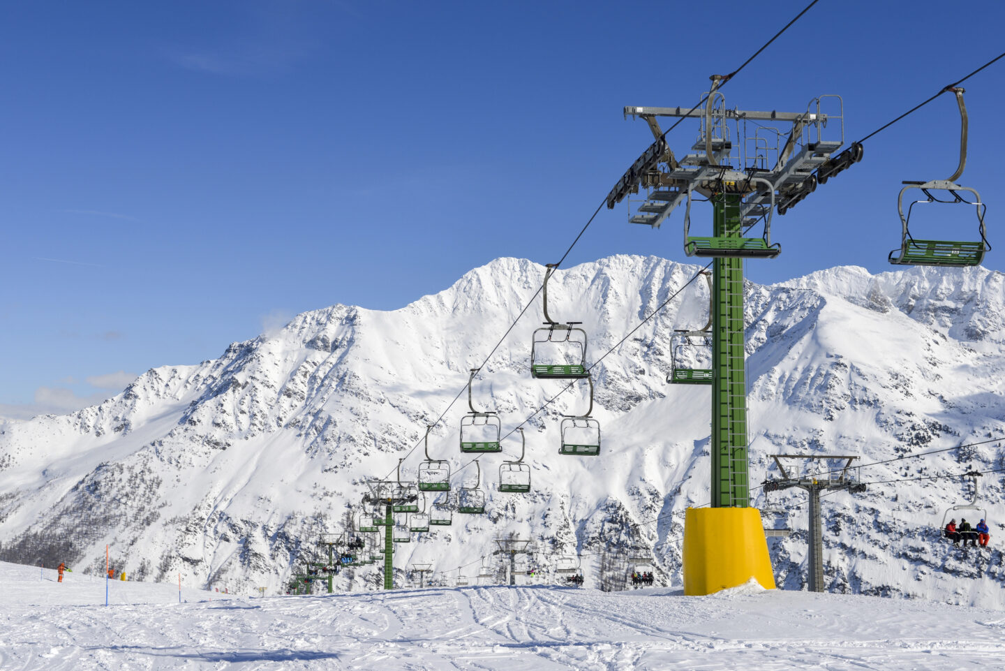 Chairlifts at La Thuile ski resort in Italy surrounded by snow-covered Alpine mountains under a clear blue winter sky.
