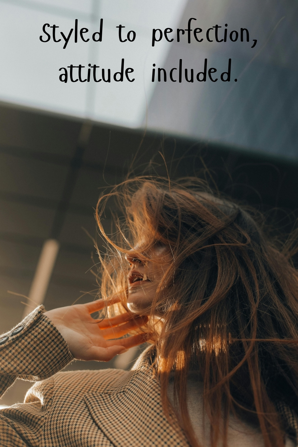 Woman with tousled hair in warm sunlight wearing a coat with the quote “Styled to perfection, attitude included.”