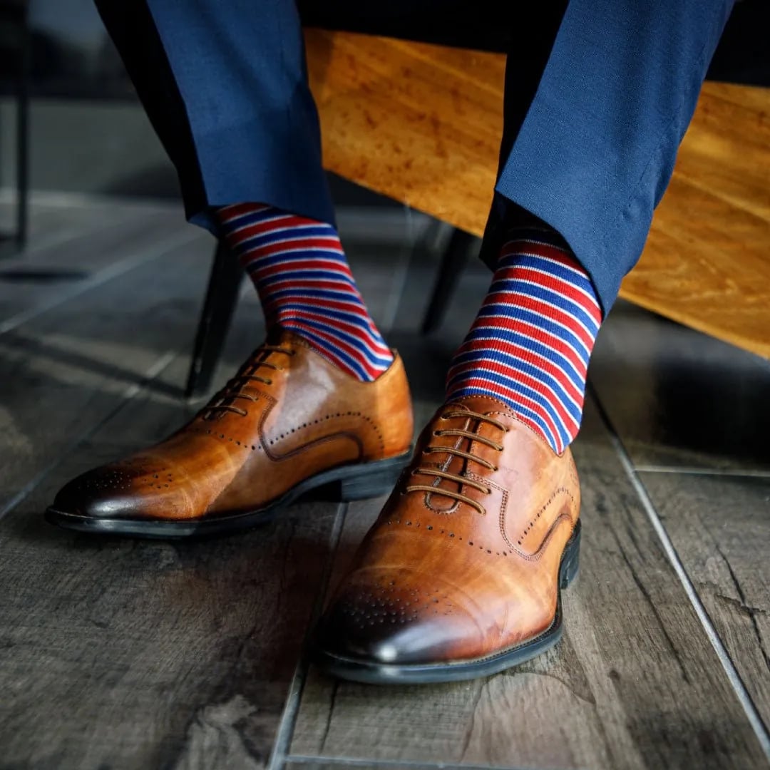 Brown leather dress shoes paired with colorful striped socks, showing how subtle accessories can add personality to professional attire.