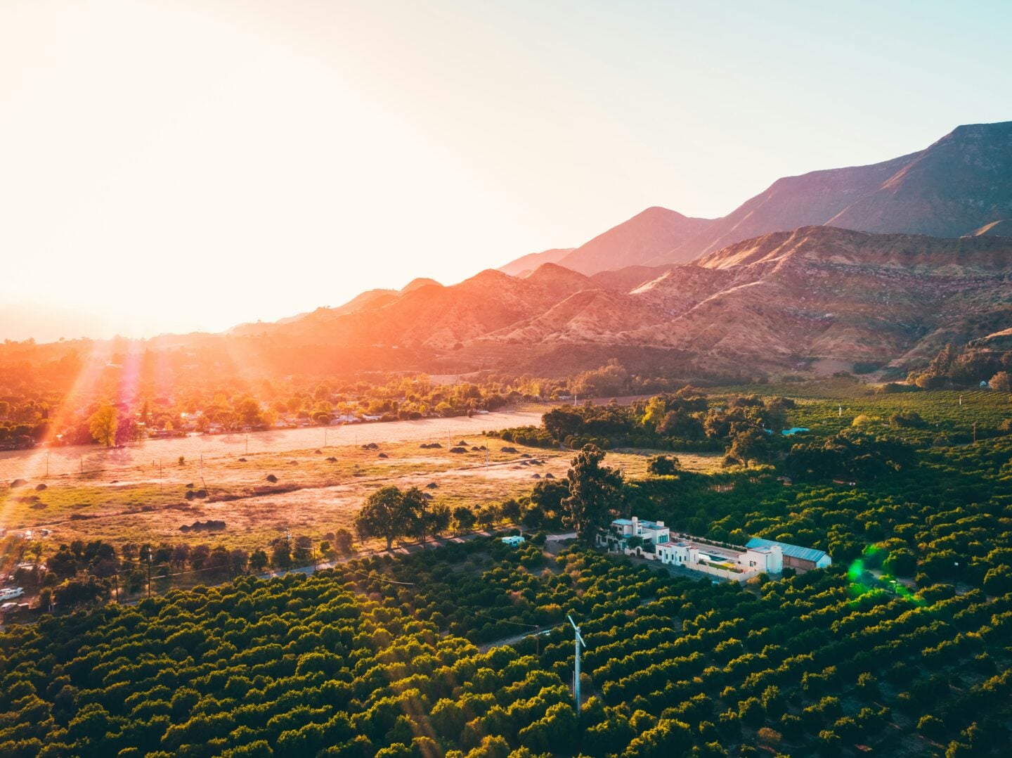 Aerial view of Ojai Valley with orchards, rolling hills, and mountain scenery at sunset in Ojai, California, USA.