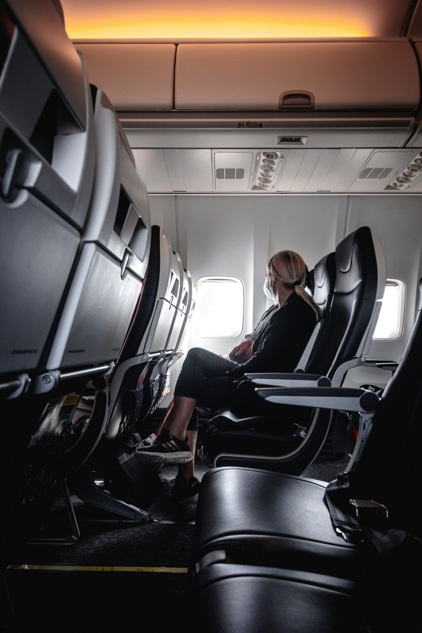 Passenger seated on an airplane during a long flight, highlighting the effects of prolonged sitting while traveling.