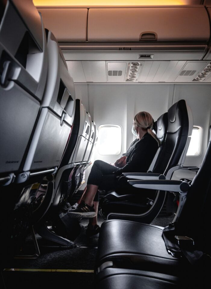 Passenger seated on an airplane during a long flight, highlighting the effects of prolonged sitting while traveling.