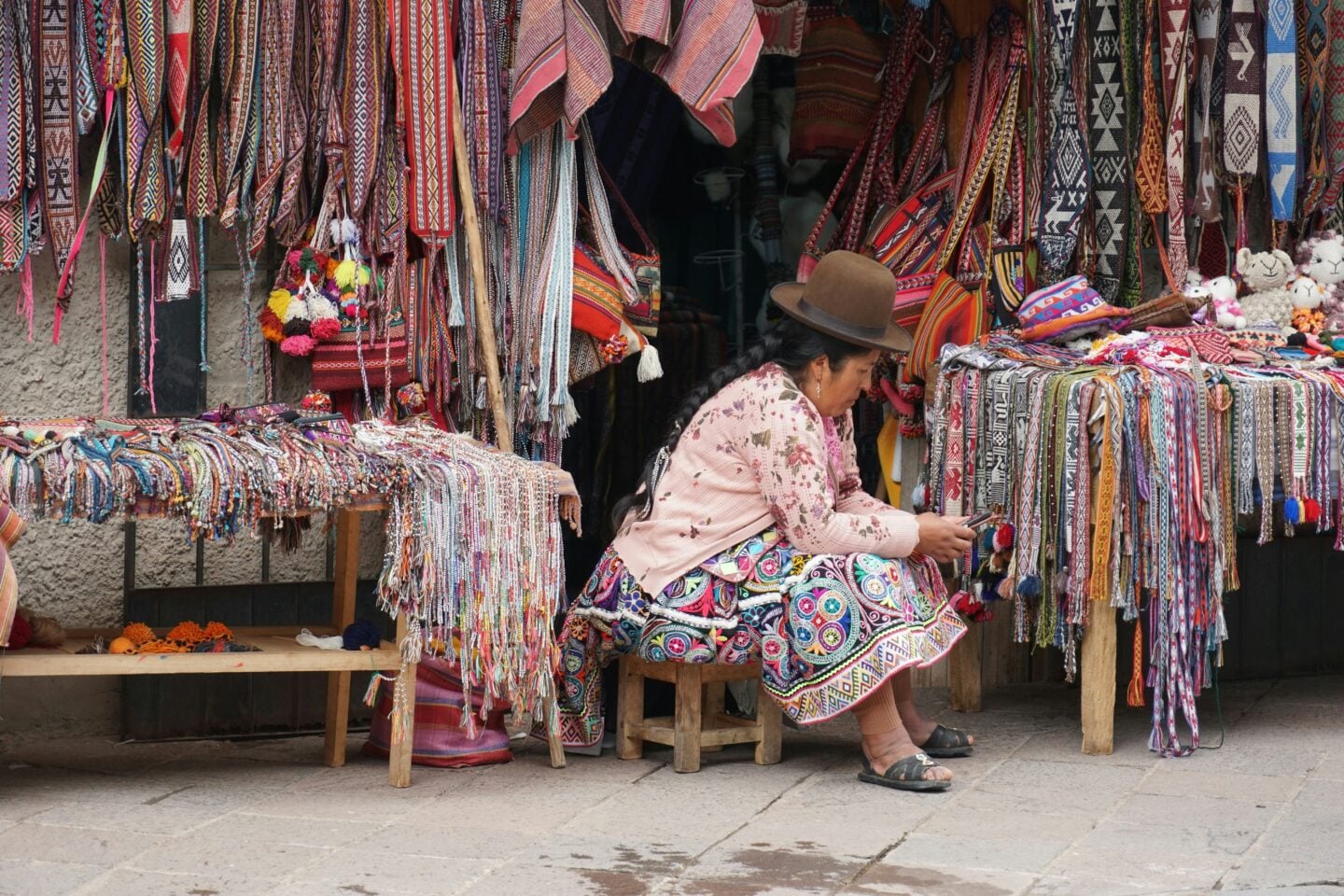 Woman selling colourful handmade textiles and woven crafts at a traditional local market.
