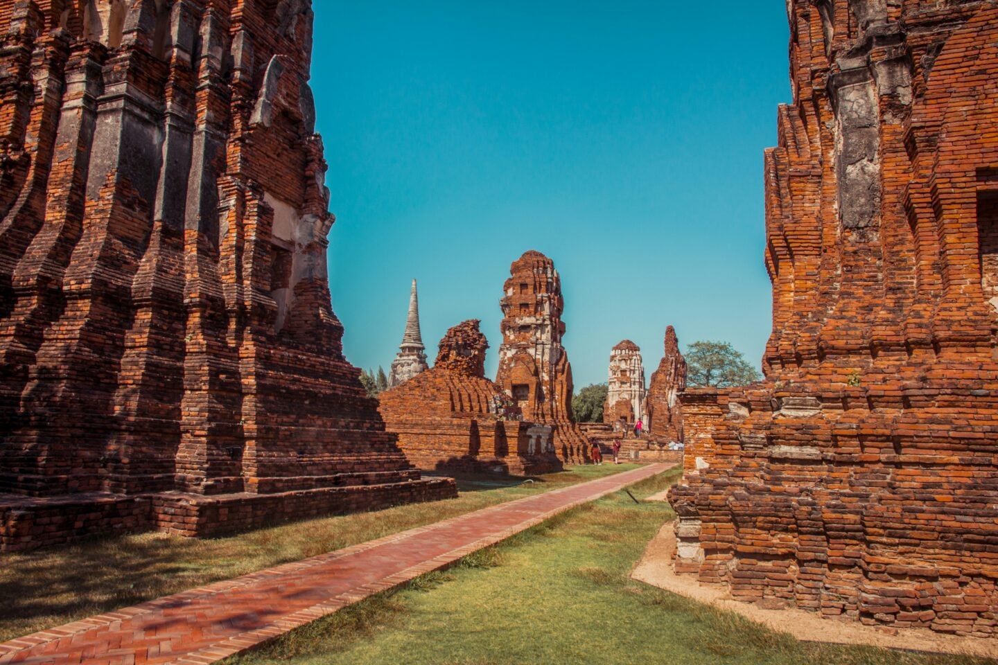 Ancient brick temple ruins at Ayutthaya Historical Park in Thailand under a clear blue sky.
