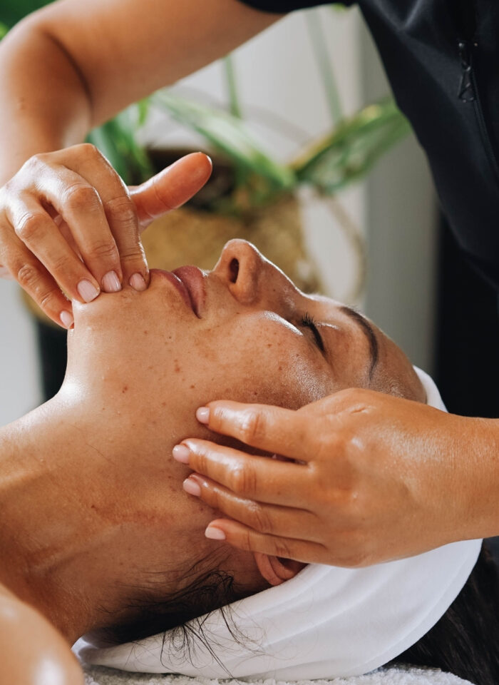 Beauty therapist performing a relaxing facial massage during a professional skincare treatment at a wellness clinic.
