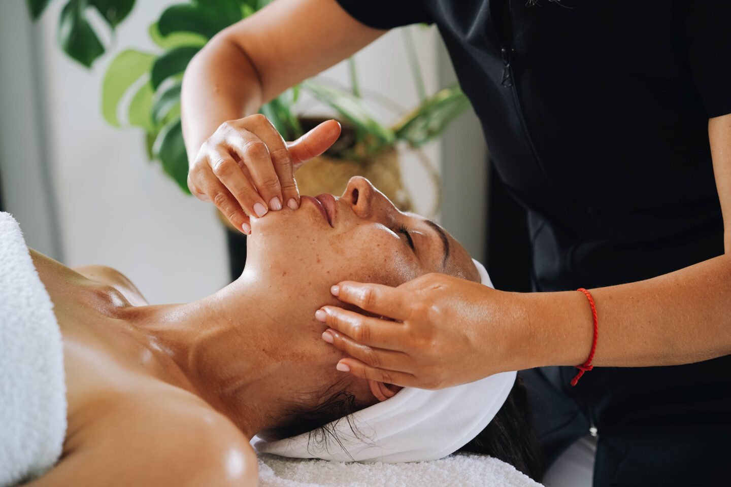 Beauty therapist performing a relaxing facial massage during a professional skincare treatment at a wellness clinic.