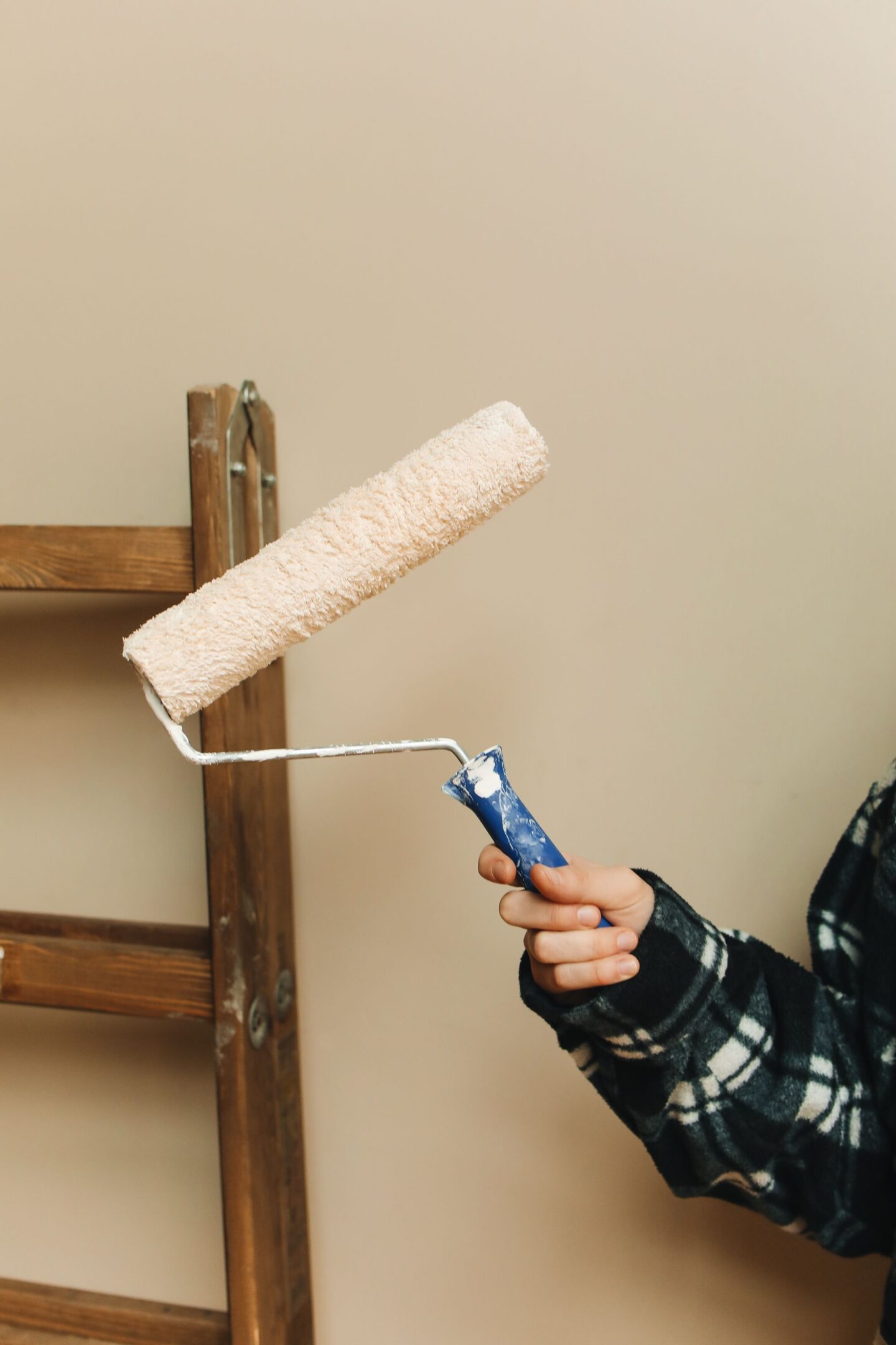 Person holding a paint roller while preparing to paint an interior wall.