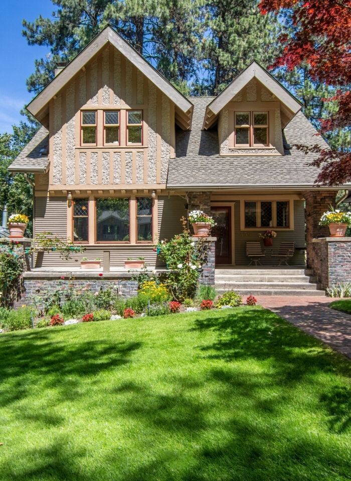 Traditional detached house with a manicured front lawn, landscaped flower beds, brick entrance path, and strong kerb appeal.