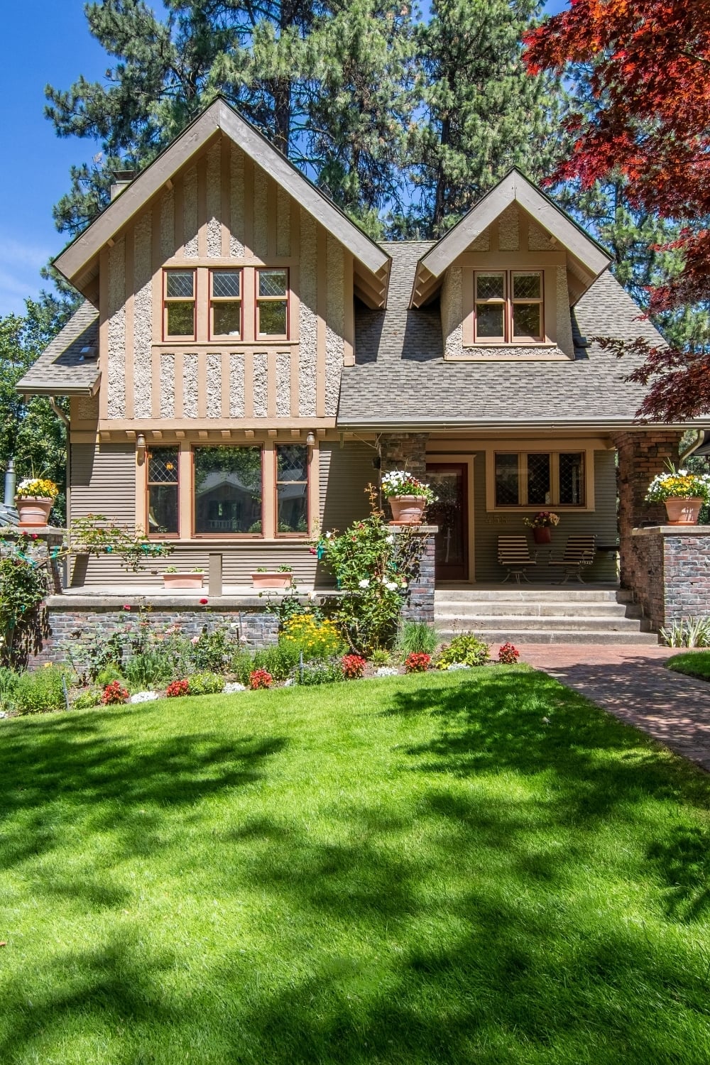 Traditional detached house with a manicured front lawn, landscaped flower beds, brick entrance path, and strong kerb appeal.
