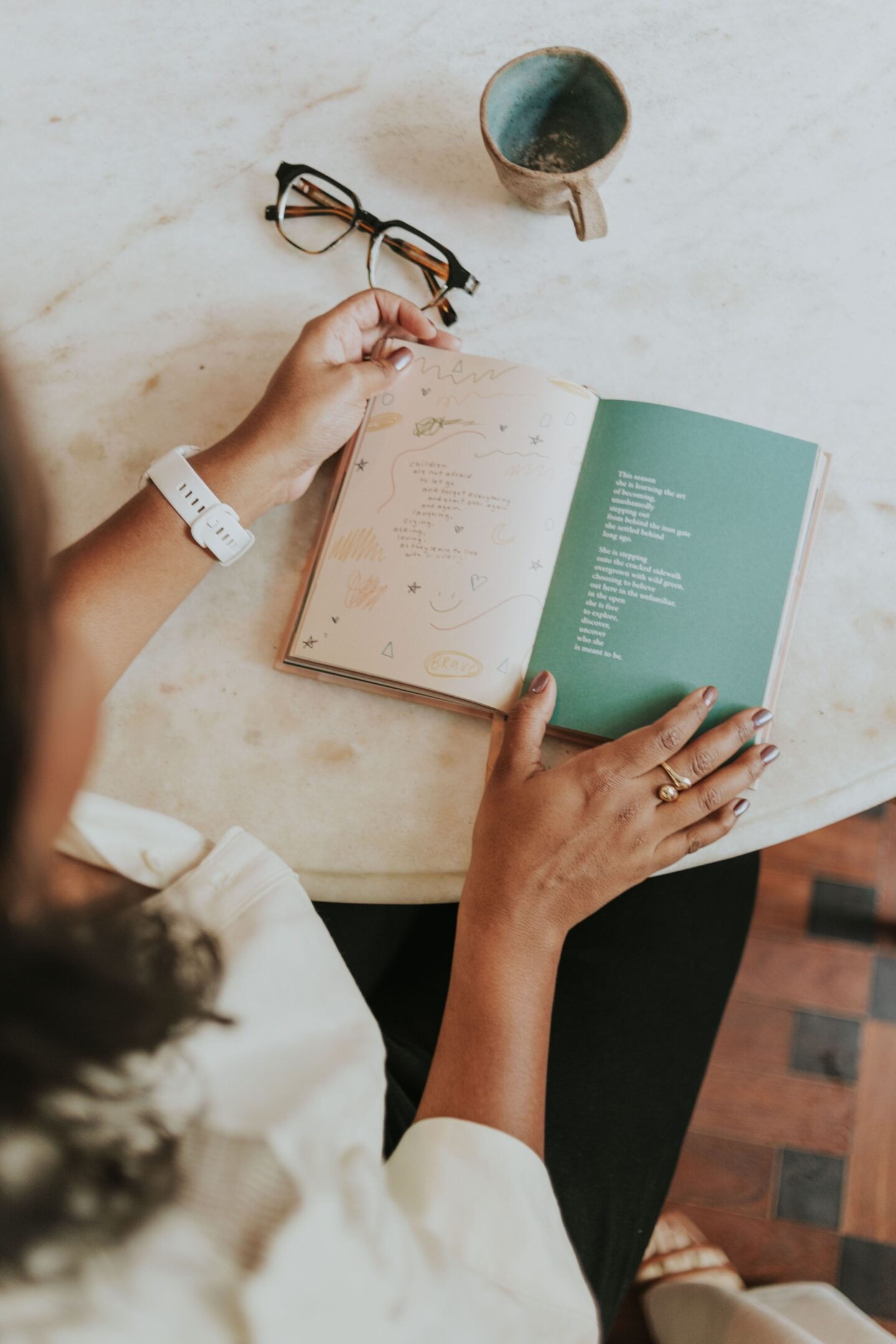 Person reading a poetry book at a table with a cup of coffee, illustrating a mindful reading practice for relaxation and self-reflection.