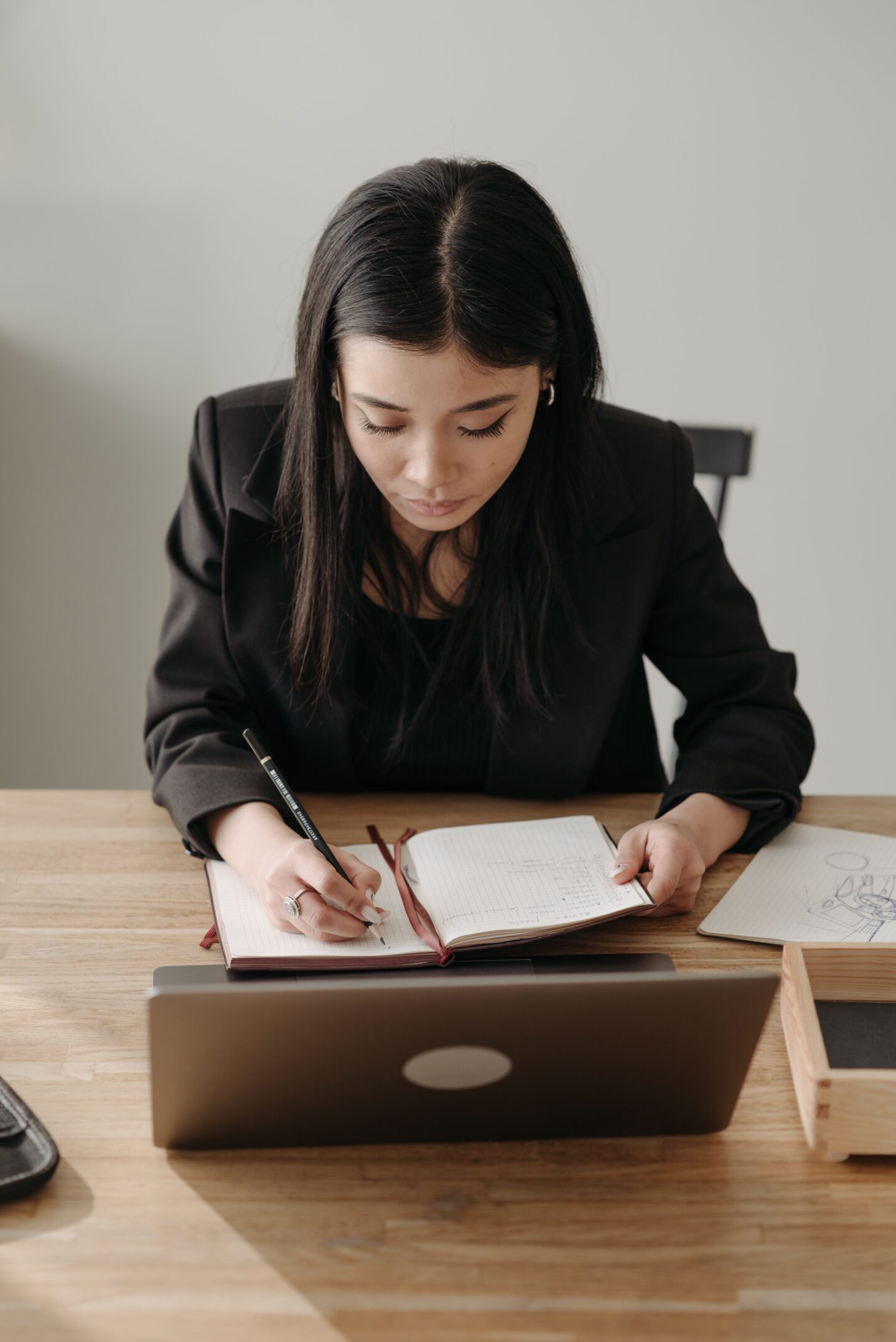 Business owner reviewing notes and planning growth strategy while working at a laptop in a home office.