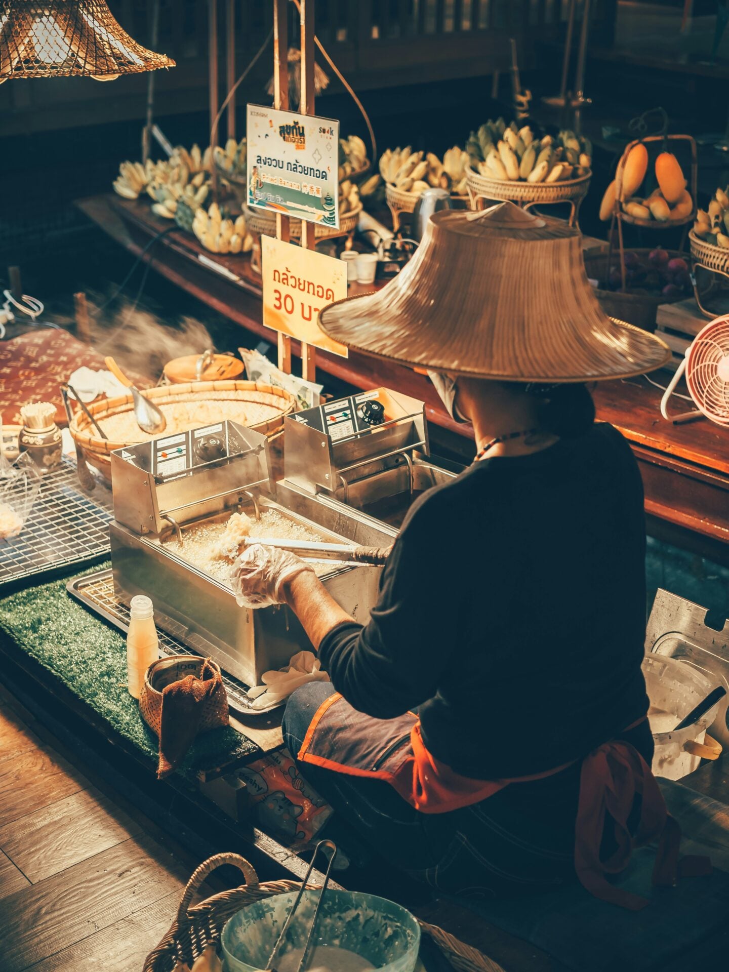 Street food vendor preparing food at a busy night market in Thailand.