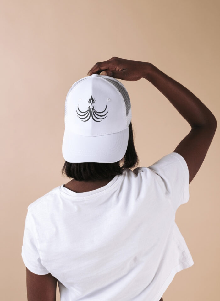 Person wearing a white custom trucker hat featuring a unique black logo design, viewed from the back.
