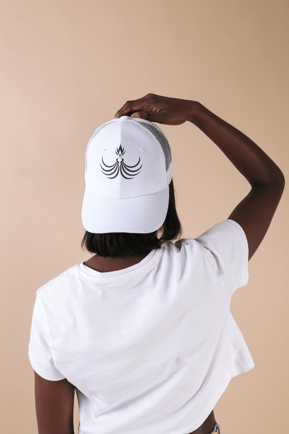 Person wearing a white custom trucker hat featuring a unique black logo design, viewed from the back.