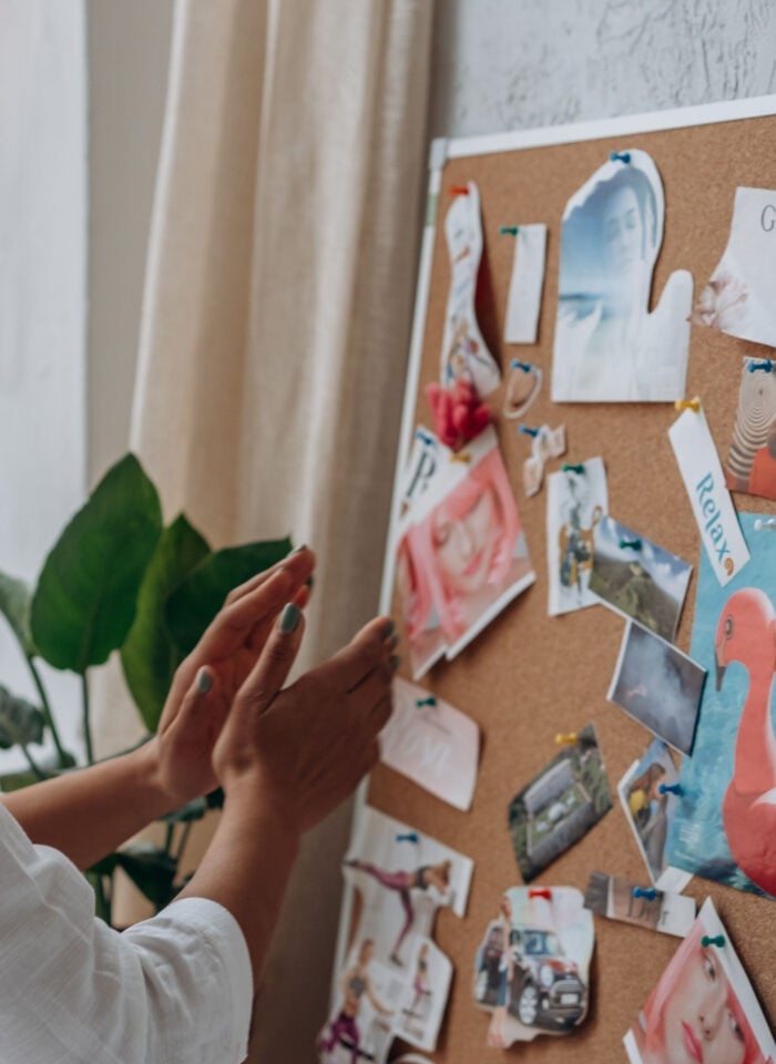 Woman creating a vision board with magazine cutouts as a relaxing DIY project.