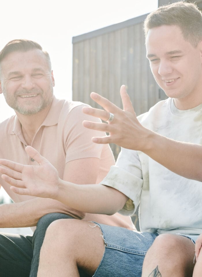 Father sitting outdoors and talking with two teenage sons about preparing for adulthood and independence.