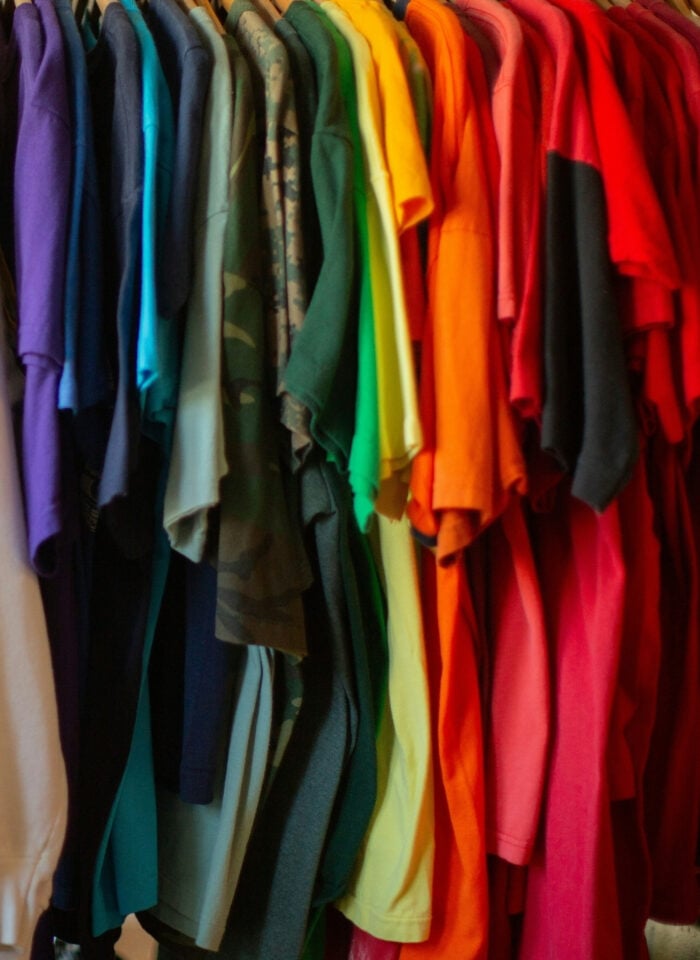 Colorful clothes in a range of bright and neutral shades hanging on a wardrobe rail.