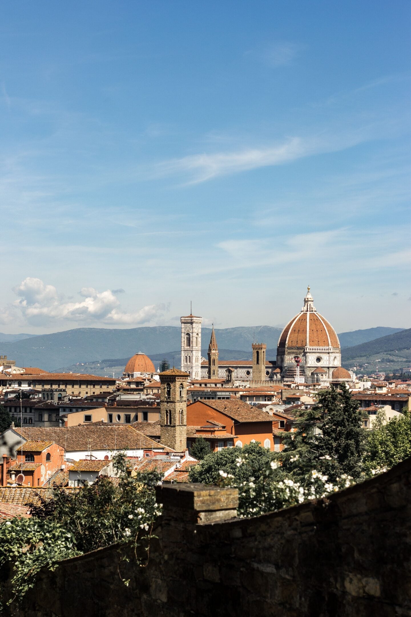 Panoramic view of Florence with the Duomo (Cathedral of Santa Maria del Fiore) and historic rooftops under a clear blue sky.