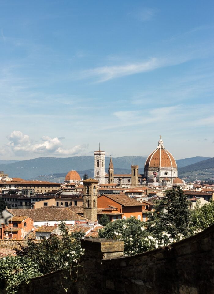 Panoramic view of Florence with the Duomo (Cathedral of Santa Maria del Fiore) and historic rooftops under a clear blue sky.