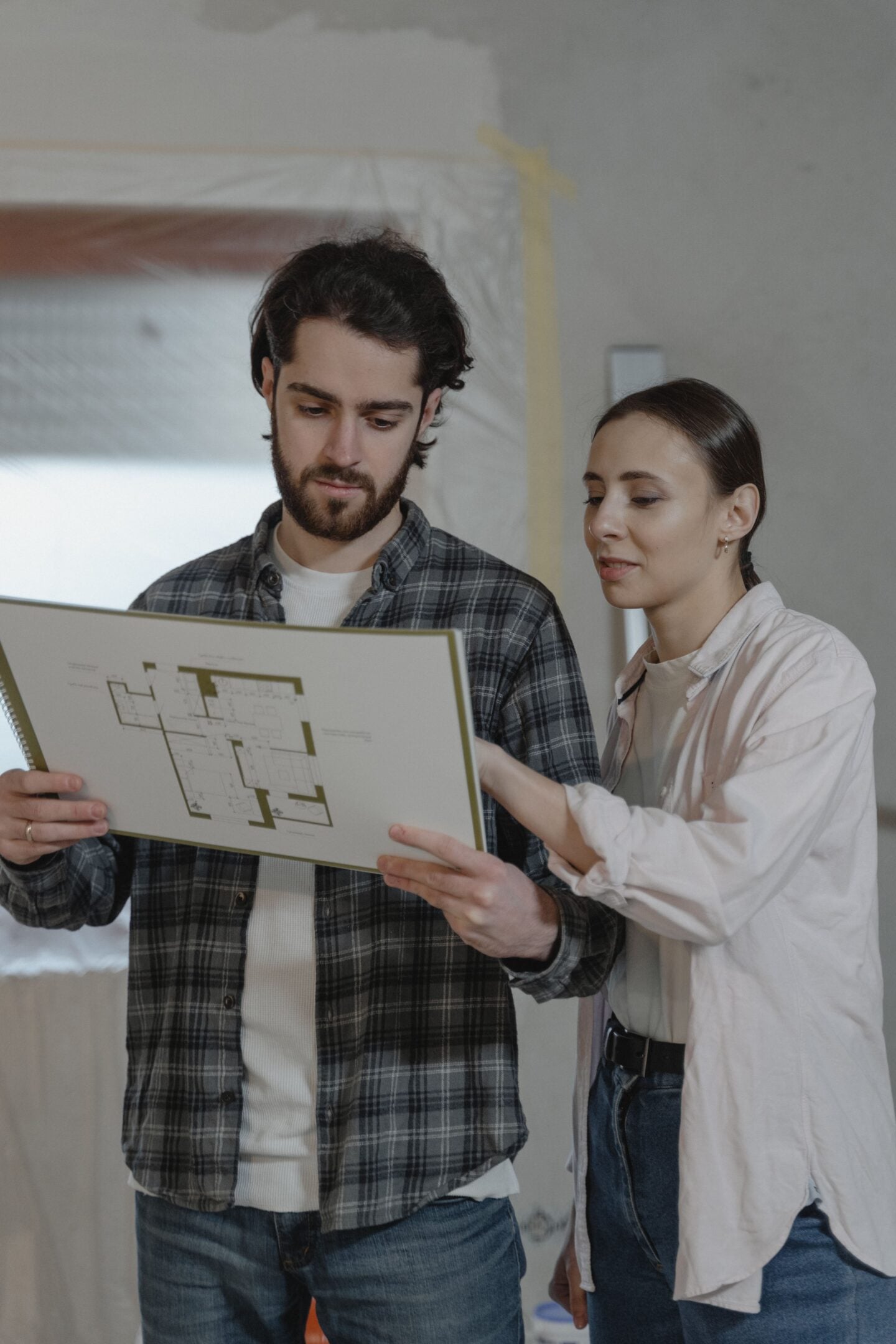 Homeowners reviewing renovation plans together while planning a major home improvement project and budgeting for upgrades.