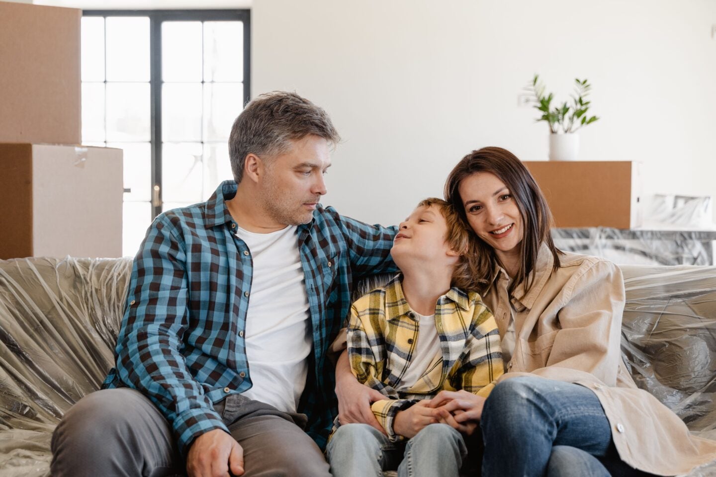 Family sitting together in their new home surrounded by moving boxes.