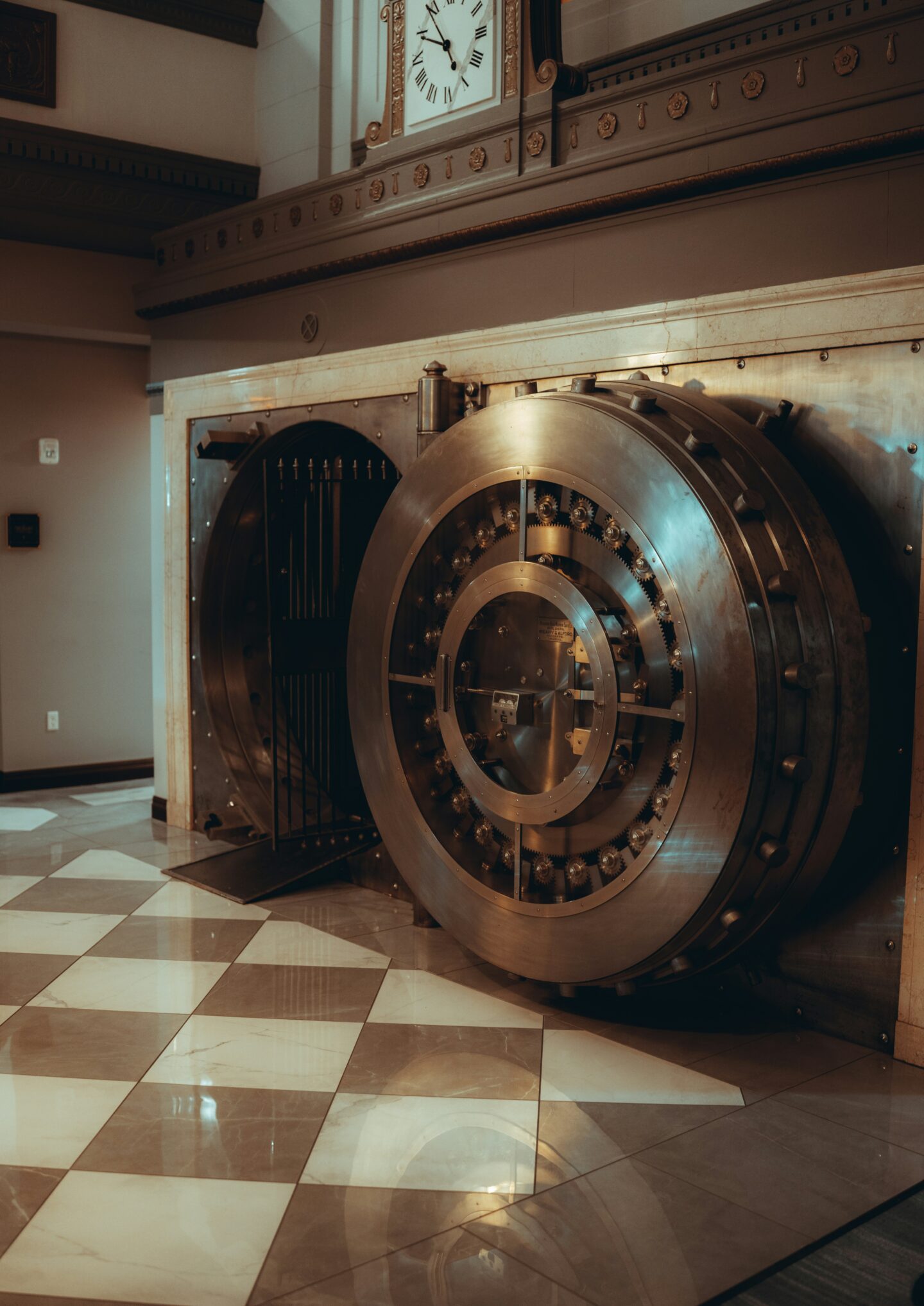 Large open bank vault with a heavy circular steel door and visible mechanical locking system inside a secure facility.