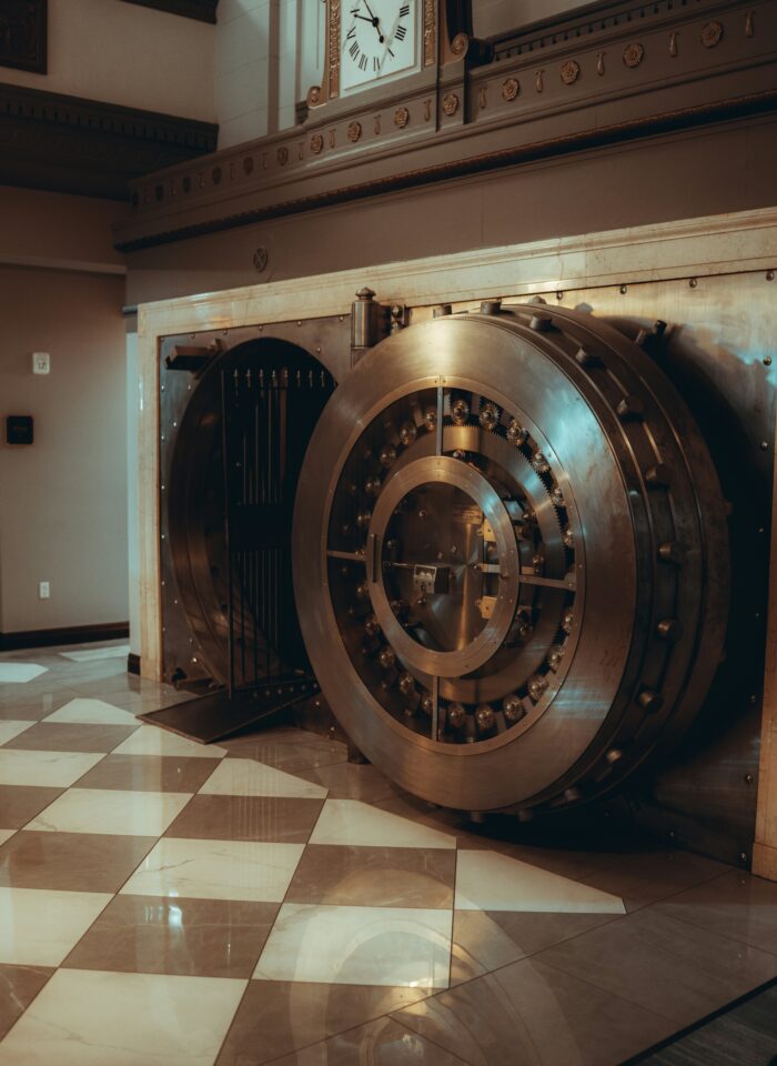 Large open bank vault with a heavy circular steel door and visible mechanical locking system inside a secure facility.