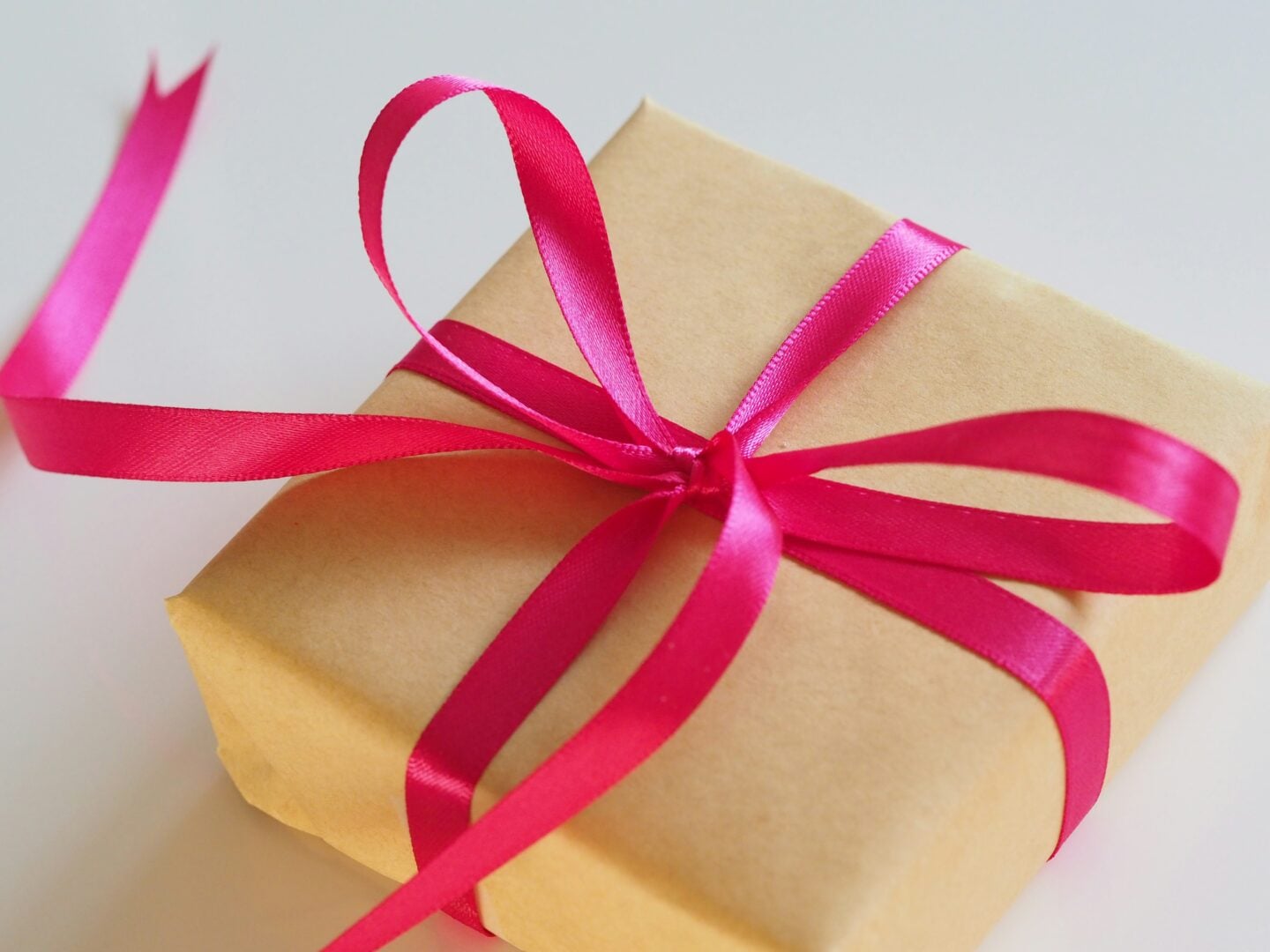 Gift wrapped in brown paper with a bright pink ribbon, representing a thoughtful personal gift.
