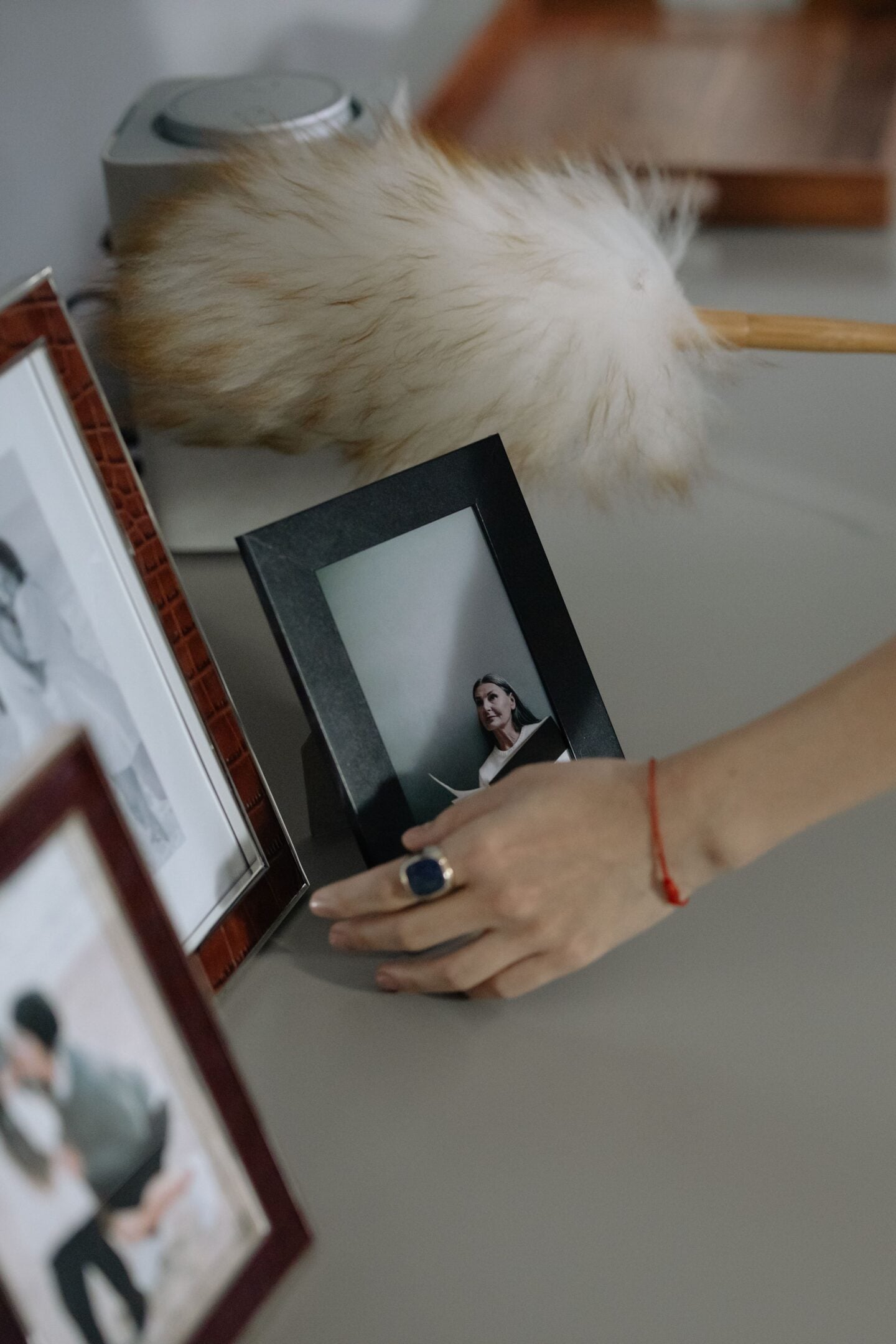 Woman arranging framed photographs on a shelf as part of a personal photo display.