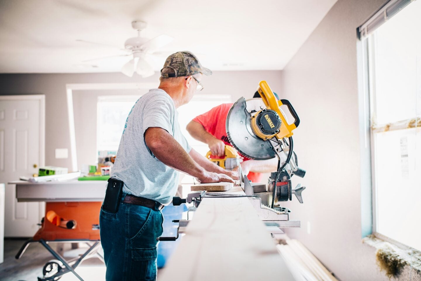 Two workers using a miter saw during a home renovation project.