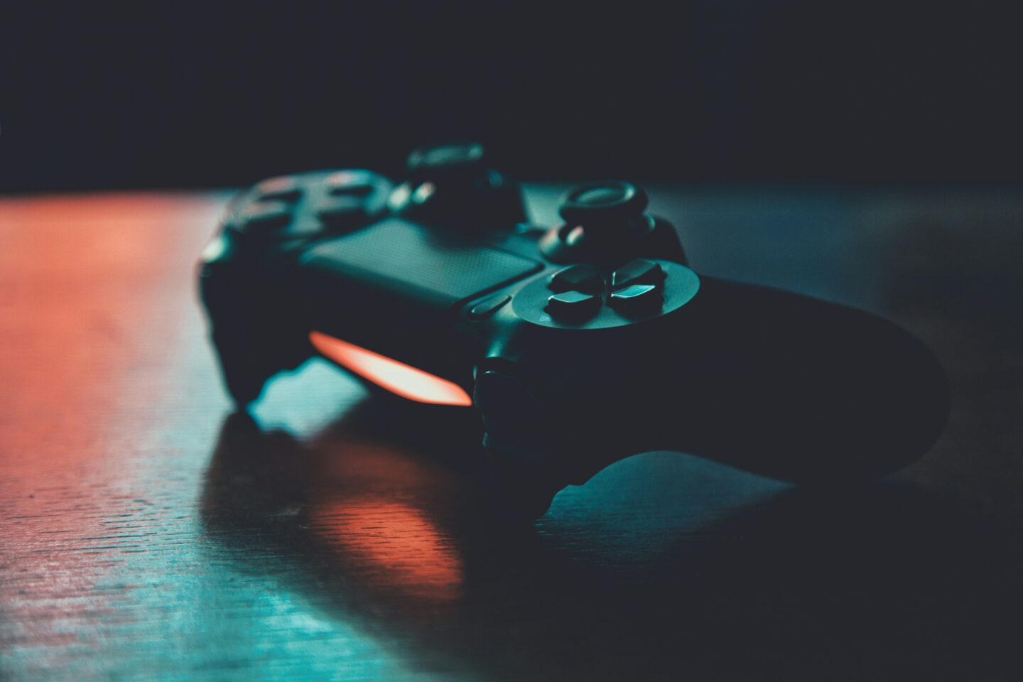 Close-up of a game controller glowing with colored light on a dark surface.