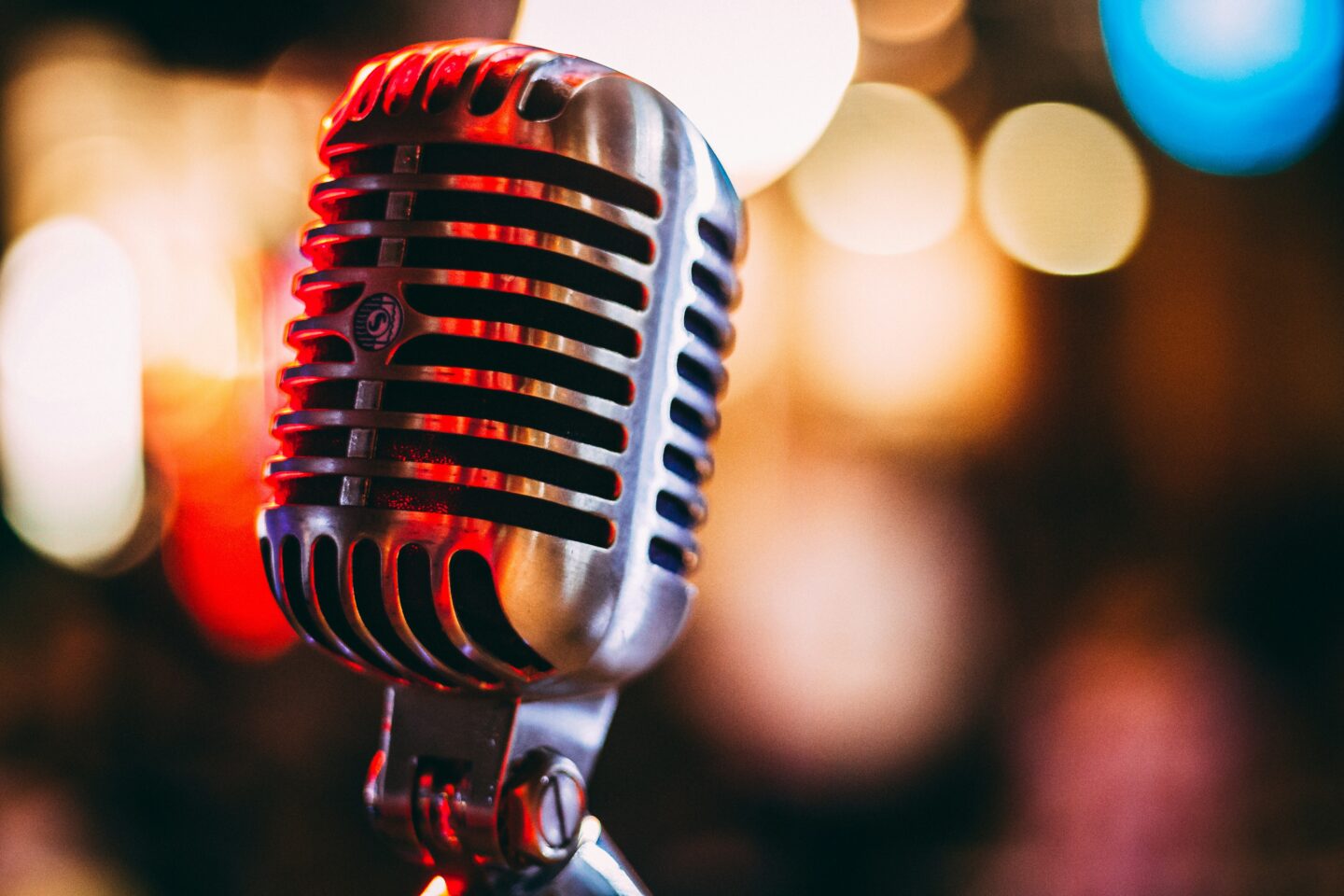 Silver karaoke microphone with colorful blurred lights in the background.