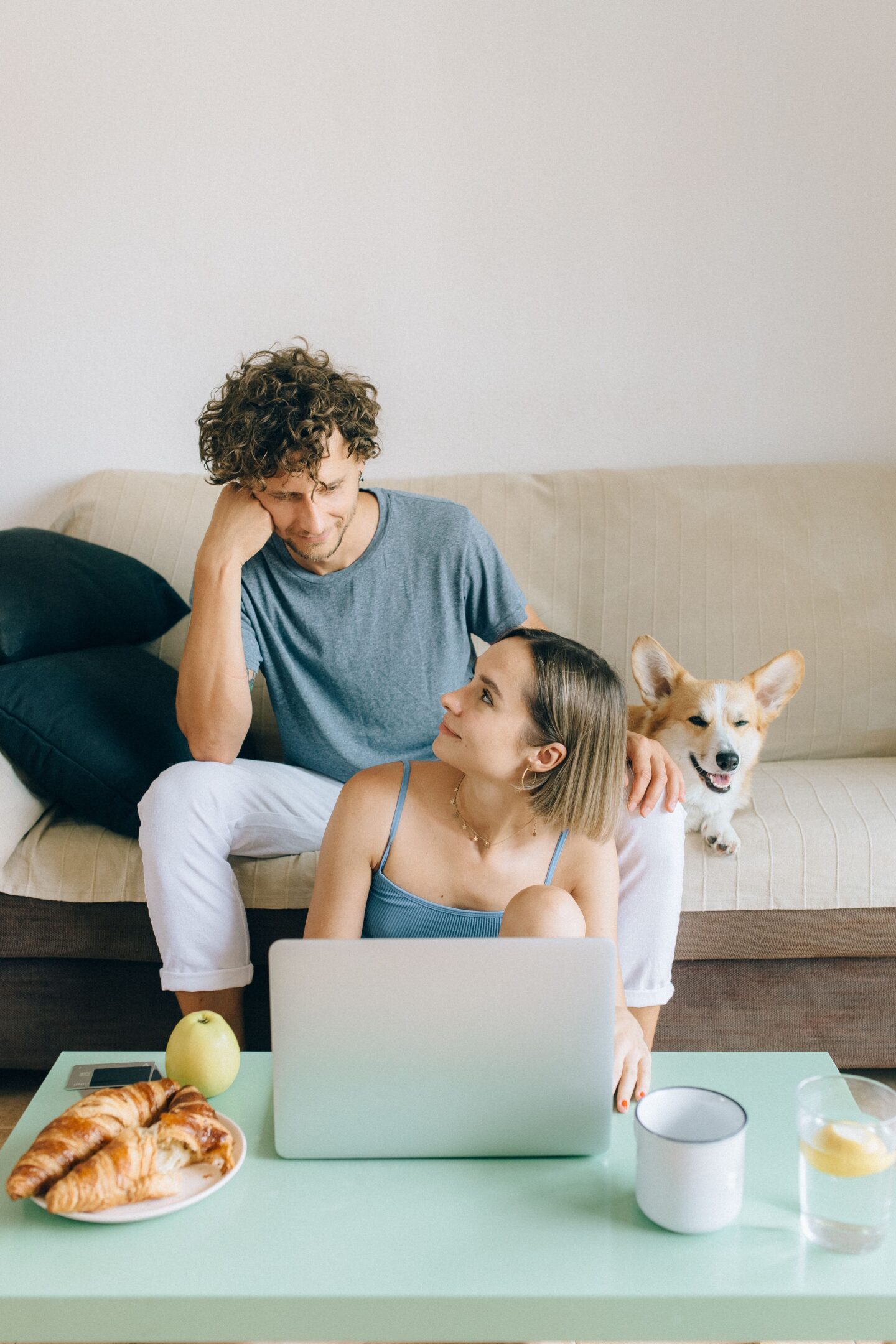 Couple reviewing their finances together on a laptop at home with their dog beside them.