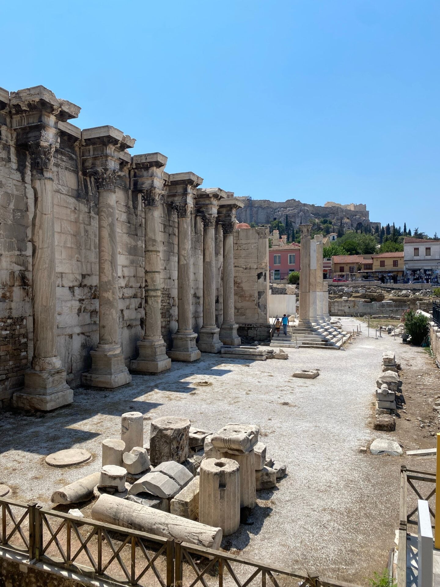 Hadrian’s Library: Standing columns and weathered stone walls of Hadrian’s Library in Athens, with scattered architectural fragments in the foreground and the Acropolis beyond.